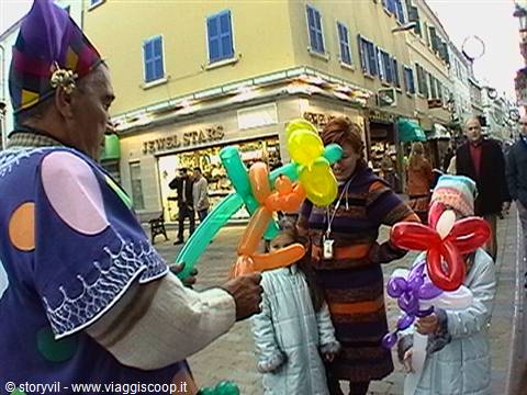 Balloon artist shapes colorful figures for a child on a pedestrian street