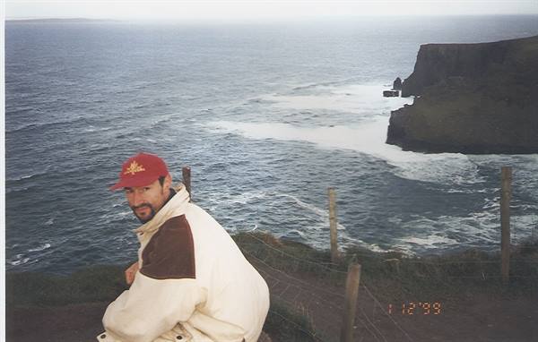 Man in red cap at the Cliffs of Moher, cliffs over the ocean