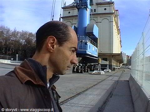 Man in foreground beside a large blue mobile crane in front of a pale building