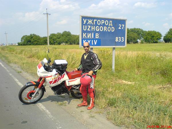 Yamaha motorcycle beside road sign showing Uzhgorod 27 and Kyiv 833
