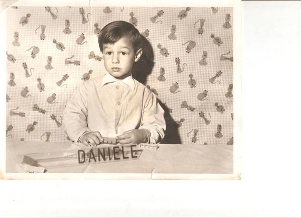 1950s studio portrait of boy Daniele against wallpaper patterned with kittens