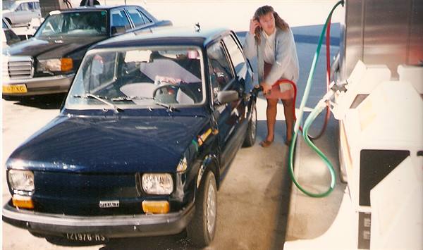 Woman refueling a blue Fiat Panda next to a Mercedes at a gas station