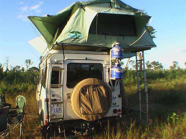 White 4x4 with green rooftop tent open and ladder, camping in the bush