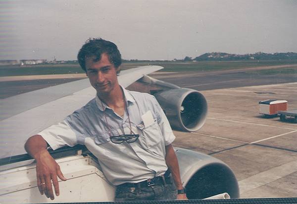 Young man leaning from airplane door, engine and tarmac behind him