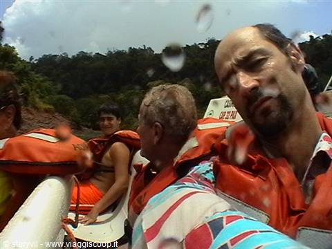Tourists in orange life jackets on dinghy, water drops on the camera lens