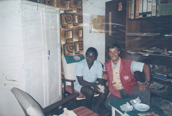 Two smiling men sitting in a room with white wardrobe and shelves
