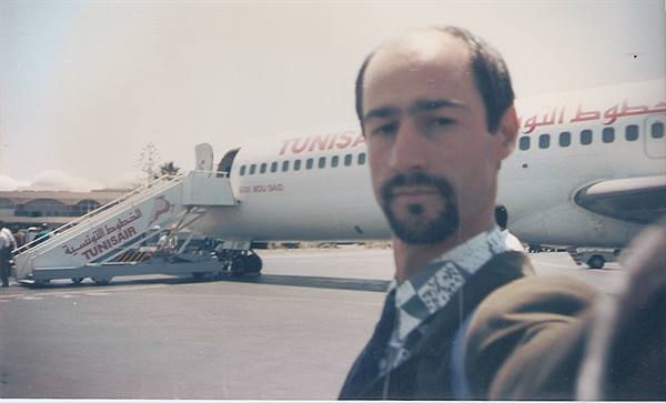 Man in front of a Tunair plane parked on the airport tarmac