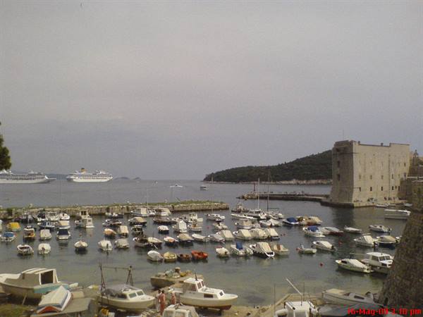 Dubrovnik old harbor full of boats, stone fortress and cruise ships