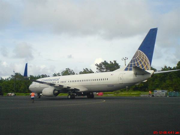 Continental airplane on the tarmac with clouds and trees behind