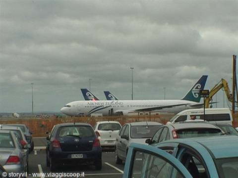 Air New Zealand plane parked at the airport, cars in front, cloudy sky