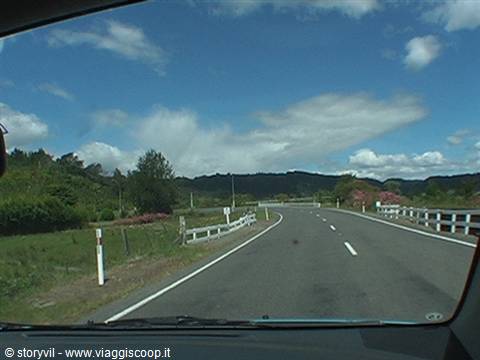 Winding asphalt road with white guardrails seen through the windshield