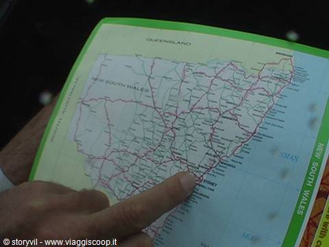Finger pointing at Sydney on a New South Wales road map