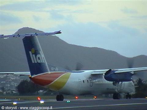 LIAT aircraft V2-LEU taxiing on tarmac, mountains and runway lights in background