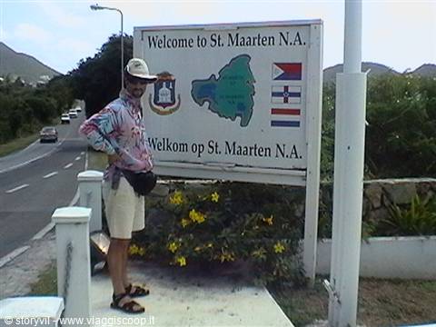 Man in hat standing beside the St. Maarten welcome sign