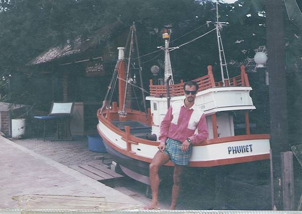 Tourist leaning on a moored fishing boat labeled Phuket