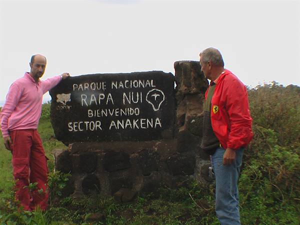 Two men beside the stone sign of Rapa Nui National Park, Anakena sector