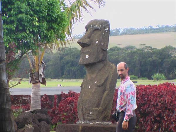 Man standing beside a volcanic stone moai, Rapa Nui