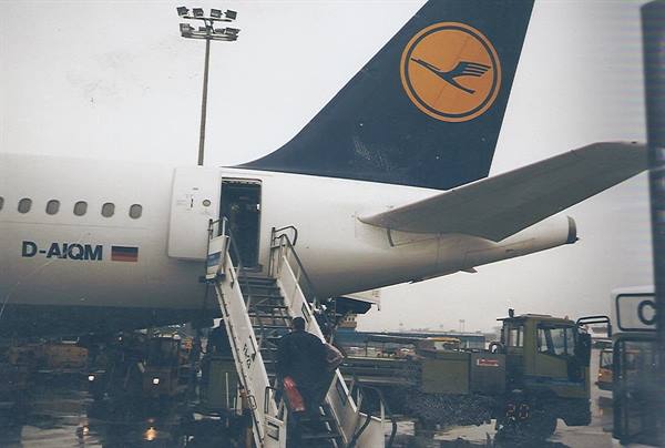 Passengers climb the airstair of a Lufthansa plane under a grey sky