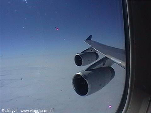 Aircraft wing and engines seen from the window above clouds