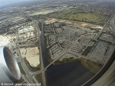 From the airplane window the engine, below suburbs, lakes and highways