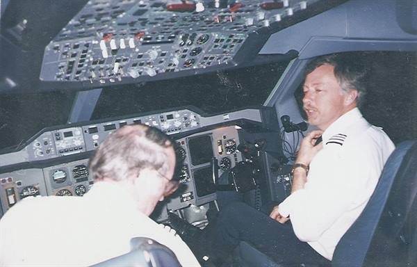 Two pilots in the cockpit, instruments lit, one speaking into the microphone