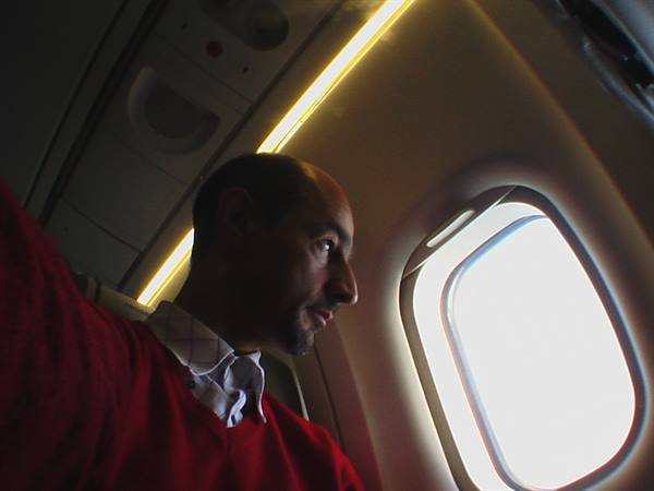 Man in red sweater beside an airplane window, warm cabin light