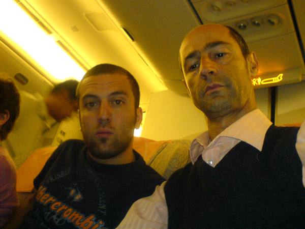 Two men sitting next to each other in airplane seats, yellow cabin lights