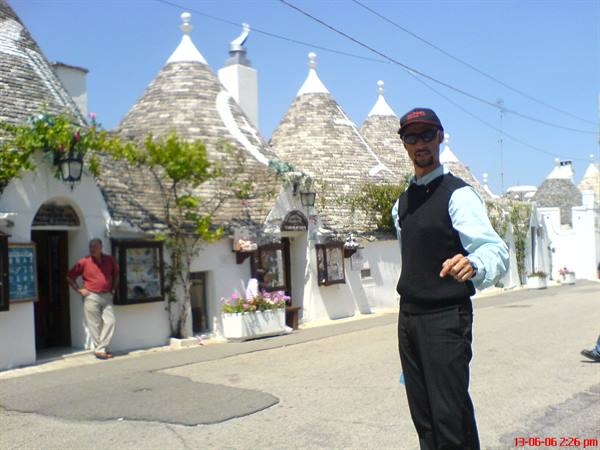 Man posing in front of Alberobello trulli, dry-stone cone-roofed houses