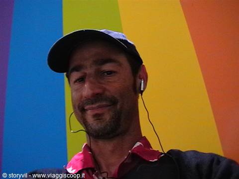Man in cap with earphones in front of colorful striped wall