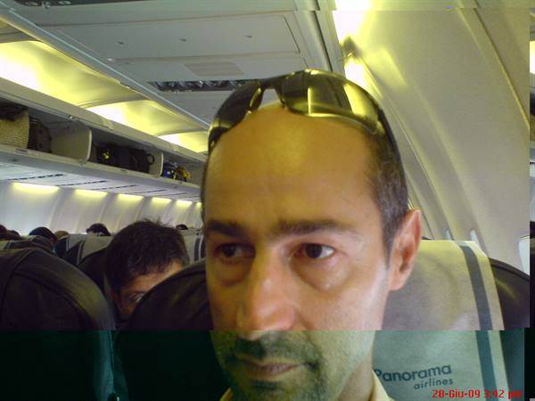 Man with sunglasses on his head seated on an airplane among passengers