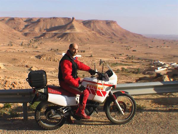 Motorcyclist in red suit on Yamaha Ténéré beside desert plateaus