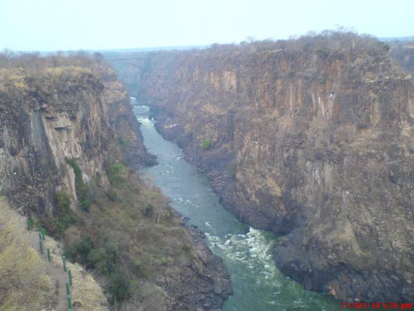 The Zambezi river flows green between rocky gorges below Victoria Falls bridge