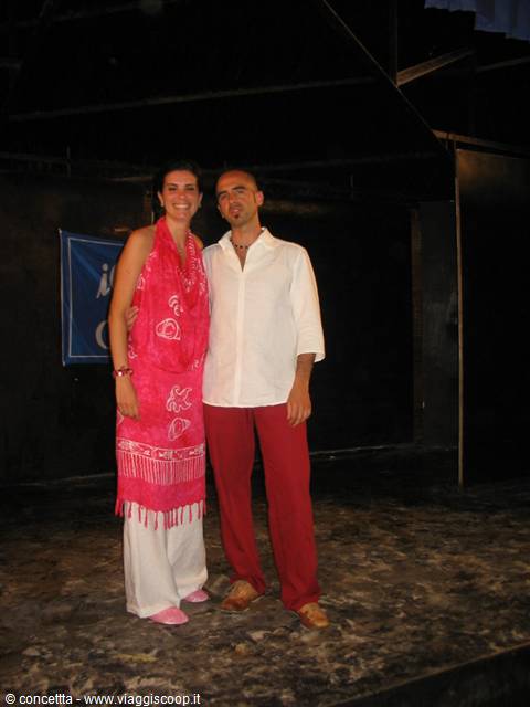 Smiling couple in white and red outfits pose outdoors at night