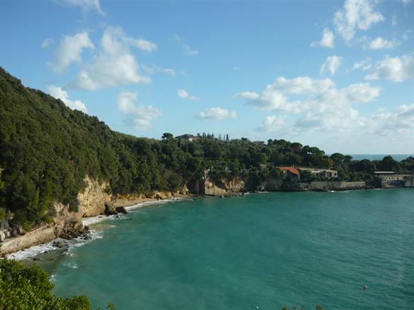 Cove with turquoise water, wooded cliffs and houses on the promontory