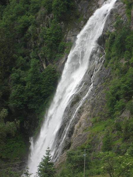 White waterfall plunging down a steep green rocky mountainside