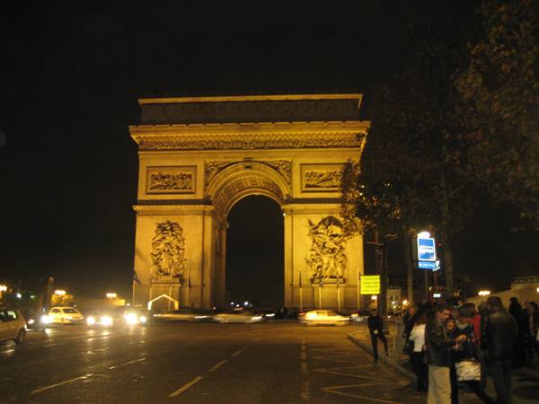 Illuminated Arc de Triomphe at night, traffic and pedestrians at Place de l'Étoile