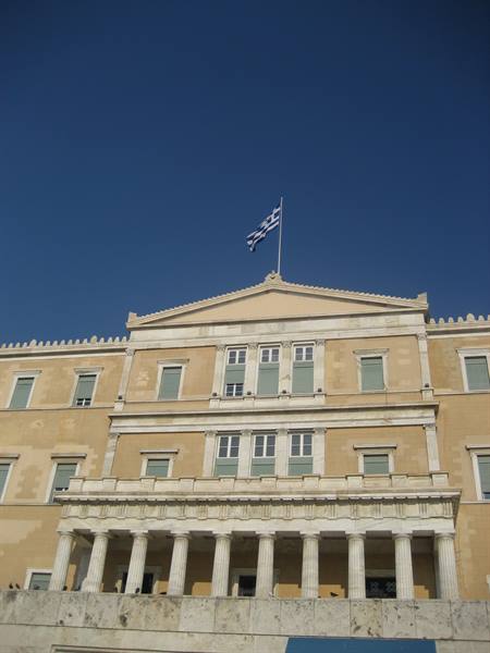 Greek flag flying over the Parliament building in Athens, marble columns