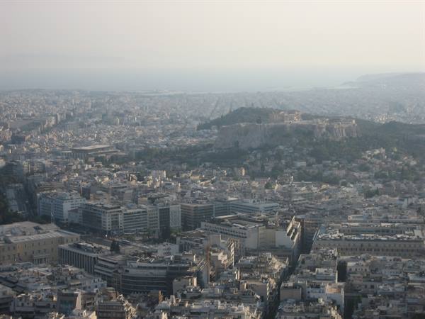 Athens: the Acropolis with snow rises among buildings under hazy light
