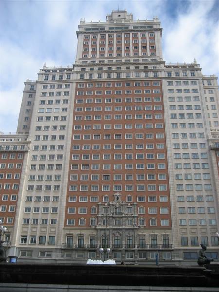 The Edificio España in Madrid, red brick and light stone facade under clouds