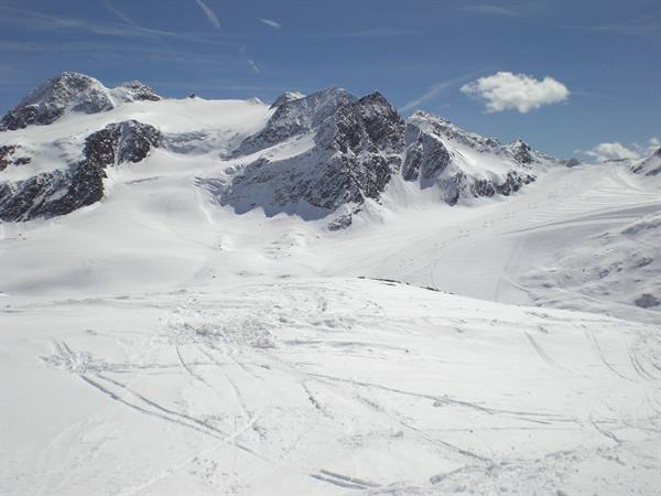 Snowy rocky peaks above a vast glacier with ski tracks