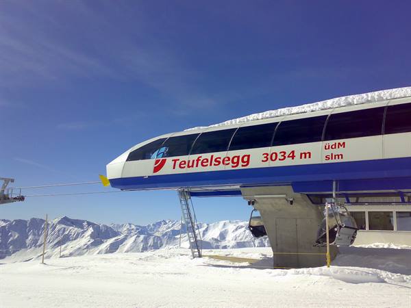 Teufelsegg cable car station at 3034 meters, snow-covered mountains under blue sky