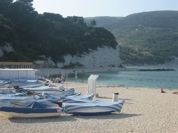 Blue-tarped fishing boats on the sandy beach beneath white limestone cliffs