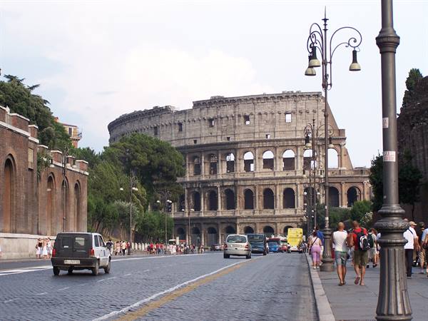 Tourists walk along the road leading to the ancient Colosseum