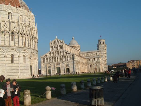 Tourists on the lawn in front of Pisa's baptistery, cathedral and leaning tower