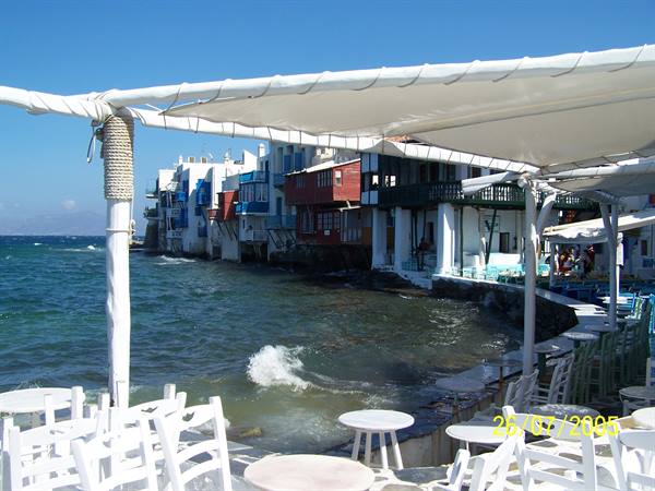 White tables under canopies, colorful houses over the sea, Mykonos Little Venice