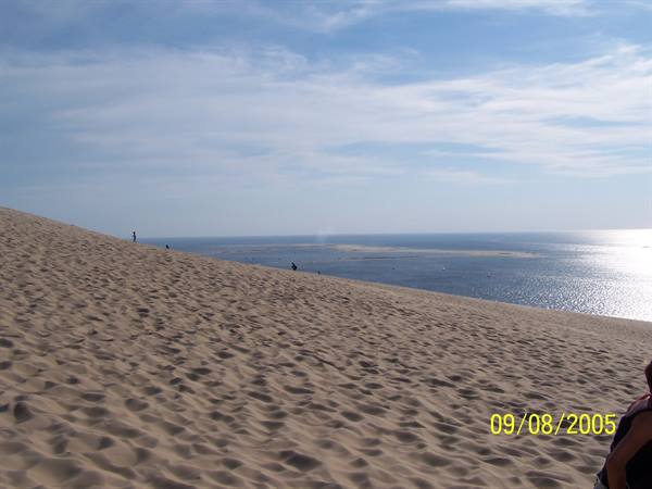 Sandy dune sloping down to the sea, a few visitors on the crest