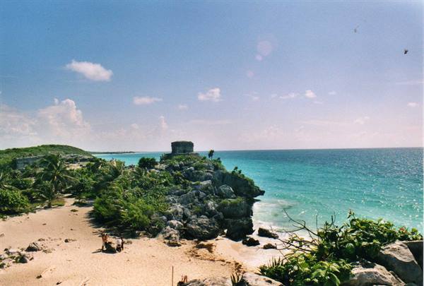 Mayan stone ruin on Tulum cliff, turquoise sea and sandy beach