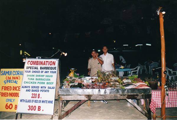 Two smiling cooks at a seafood barbecue stall, Ko Samui, at night