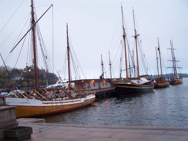 Old wooden sailing ships moored at Stockholm harbor under a grey sky
