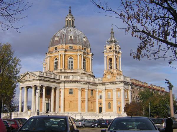Basilica di Superga in Turin, baroque dome and bell tower among autumn trees and parked cars